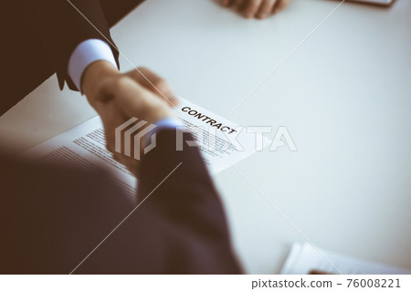 Business people shaking hands while sitting at the desk at meeting or negotiation, close-up. Group of unknown businessmen in a modern office. Teamwork, partnership and handshake concept Business people shaking hands while sitting at the desk at meeting or negotiation, close-up. Group of unknown businessmen in a modern office. Teamwork, partnership and handshake concept 76008221