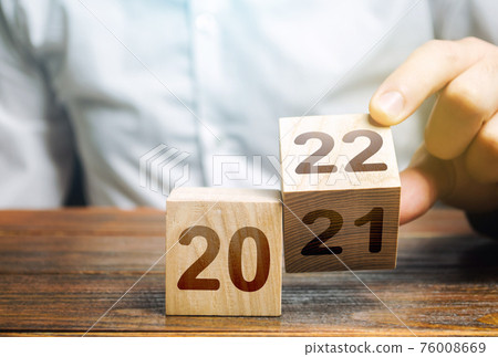Hand flips a block changing 2021 to 2022. New year beginning. Holidays and Christmas. Trends and changes in the World. Summing work done. Build plans. New normal. Keep up with everything planned. Hand flips a block changing 2021 to 2022. New year beginning. Holidays and Christmas. Trends and changes in the World. Summing work done. Build plans. New normal. Keep up with everything planned. 76008669