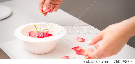 Beautician preparing manicure bath with petals 76009879