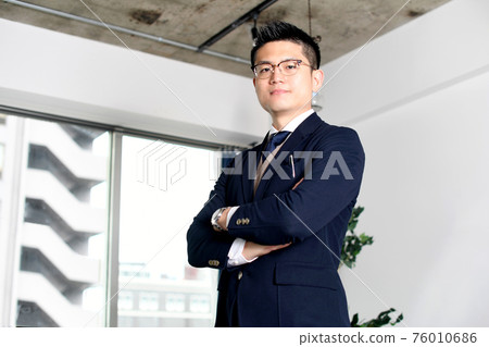 A businessman in a suit with his arms folded 76010686
