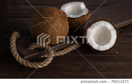 split and whole coconut on wooden planks. Coco, ripe palm fruit. copy space 76011071
