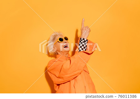Woman smiling joyfully and pointing up with the finger 76011386