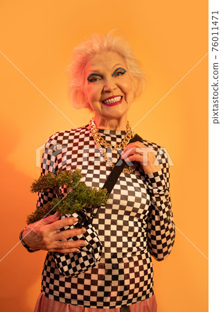 Woman keeps hands at her bag and looking directly at camera Woman keeps hands at her bag and looking directly at camera 76011471