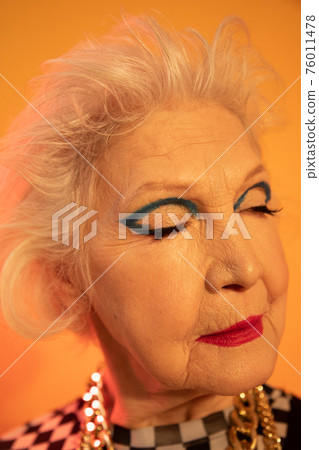 Woman dressed in trendy clothes standing with eyes closed in front of the camera 76011478