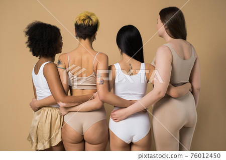 Girls with different types of shape and skin posing at the beige background Girls with different types of shape and skin posing at the beige background 76012450