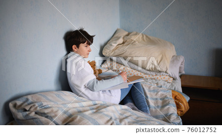 Poor sad small girl on bed indoors at home, poverty concept. Poor sad small girl on bed indoors at home, poverty concept. 76012752