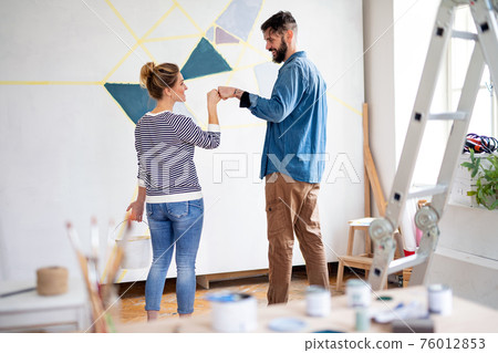 Couple having fun when painting wall indoors at home, relocation and diy concept. Couple having fun when painting wall indoors at home, relocation and diy concept. 76012853