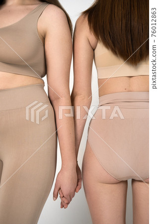 Girls standing in front of the camera and holding hands of each other 76012863