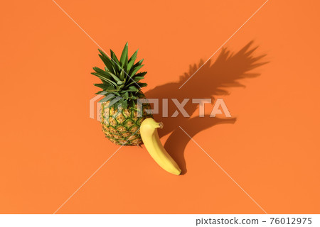 Summer fruits on an orange background. Banana and pineapple minimalist. Summer fruits on an orange background. Banana and pineapple minimalist. 76012975