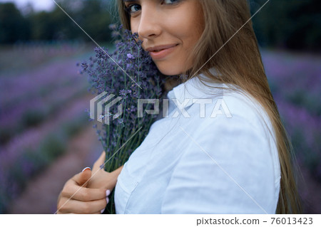 Smiling woman posing with bouquet in lavender field. 76013423
