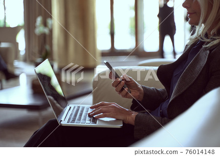 Determined lady holding her smartphone while being seated in a waiting area 76014148