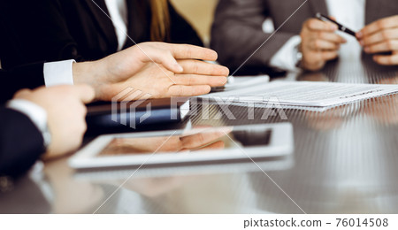 Unknown businessmen and woman sitting, using laptop computer and discussing questions at meeting in modern office, close-up 76014508