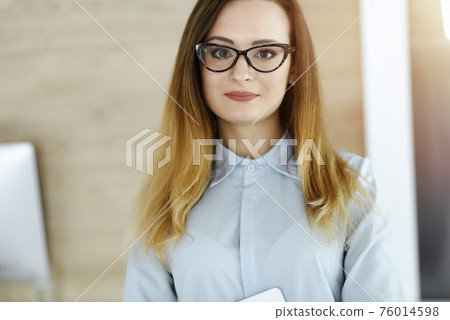 Business woman headshot in sunny office. Unknown businesswoman standing straight with tablet computer. Young accountant or secretary looks good Business woman headshot in sunny office. Unknown businesswoman standing straight with tablet computer. Young accountant or secretary looks good 76014598