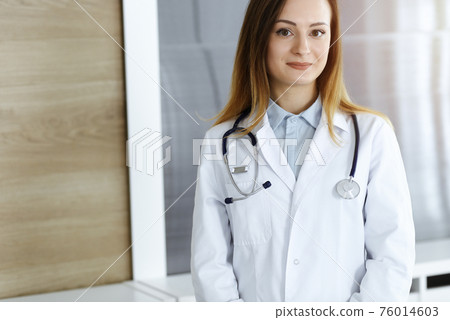 Doctor woman headshot while standing in hospital office. Physician at workplace, portrait photo. Medicine and health care concept 76014603