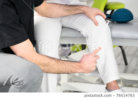 Neurological examination. The neurologist testing reflexes on a female patient using a hammer. Neurological examination. The neurologist testing reflexes on a female patient using a hammer. 76014763