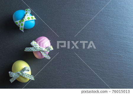 Easter flat. Colorful egg with tape ribbon on dark rough stone background in Happy Easter decoration. Spring holiday top view concept. Easter flat. Colorful egg with tape ribbon on dark rough stone background in Happy Easter decoration. Spring holiday top view concept. 76015013