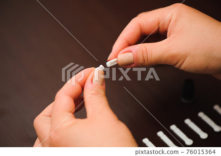 Woman taking blood sample with lancet pen on wooden background. Diabetes concept. 76015364