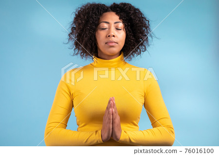 Calm african woman praying with hands together symbolizing prayer and gratitude. Mudra. Yoga concept Calm african woman praying with hands together symbolizing prayer and gratitude. Mudra. Yoga concept 76016100