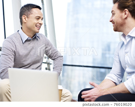 two caucasian businessmen chatting during coffee break in office two caucasian businessmen chatting during coffee break in office 76019020