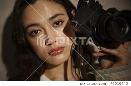 Portrait of a woman holding a classic camera Portrait of a woman holding a classic camera 76019440