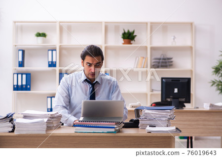 Young male employee and too much work in the office Young male employee and too much work in the office 76019643