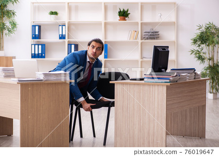 Young male employee in multitasking concept 76019647
