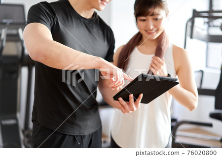 Asian male personal trainer teaching using a tablet 76020800