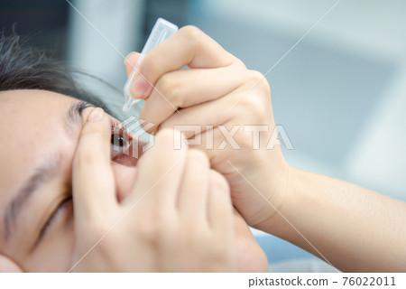Woman use eye drop, artificial tears to the eye Woman use eye drop, artificial tears to the eye 76022011