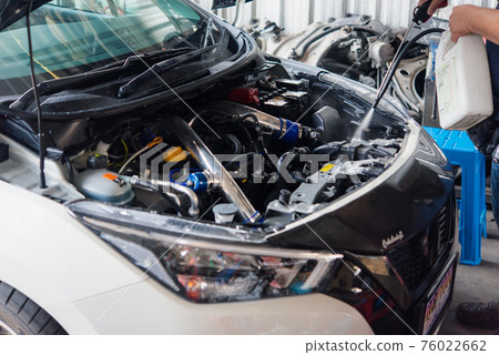 Checking a car engine for repair at car garage 76022662