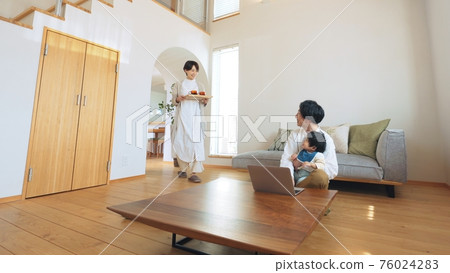 Father teleworking while babysitting in the living room 76024283