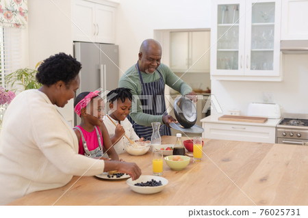 African american grandparents cooking with smiling grandson and granddaughter in kitchen African american grandparents cooking with smiling grandson and granddaughter in kitchen 76025731