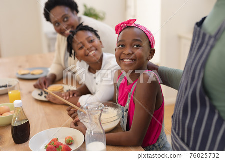 African american grandparents cooking with smiling grandson and granddaughter in kitchen African american grandparents cooking with smiling grandson and granddaughter in kitchen 76025732