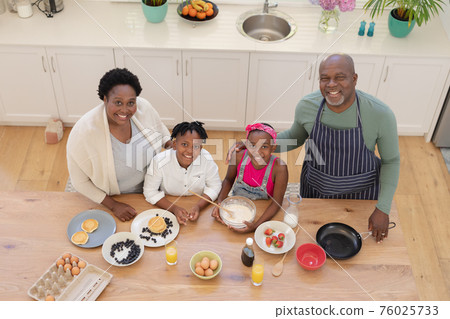 High angle portrait of african american grandparents teaching grandchildren cooking in the kitchen High angle portrait of african american grandparents teaching grandchildren cooking in the kitchen 76025733