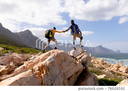 Fit afrcan american couple wearing backpacks hiking on the coast Fit afrcan american couple wearing backpacks hiking on the coast 76026592