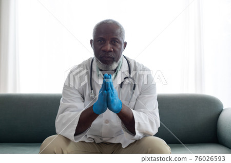 Portrait of senior african american male doctor giving patient consultation at home 76026593