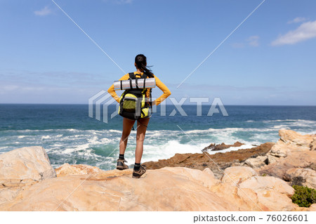 Fit afrcan american woman wearing backpack hiking on the coast 76026601