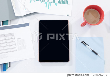 Office workstation desk with tablet computer paperwork and a cup of coffee 76026797