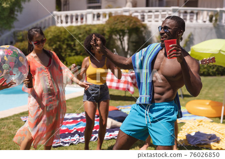 Diverse group of friends having fun and dancing at a pool party 76026850