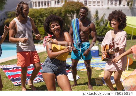 Diverse group of friends having fun and dancing at a pool party 76026854