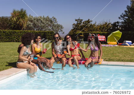 Diverse group of friends drinking beer and sitting at the poolside Diverse group of friends drinking beer and sitting at the poolside 76026972