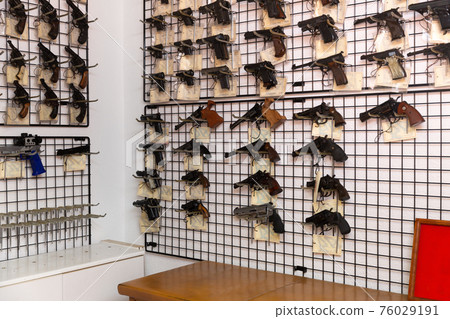 Gun shop with revolvers and pistols on showcase 76029191