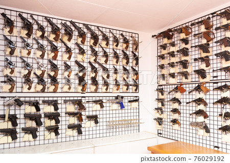 Gun shop interior with handguns displayed on rack Gun shop interior with handguns displayed on rack 76029192