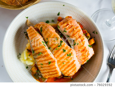 Tasty steak of grilled salmon in sauce with pepper and lemon on plate 76029392