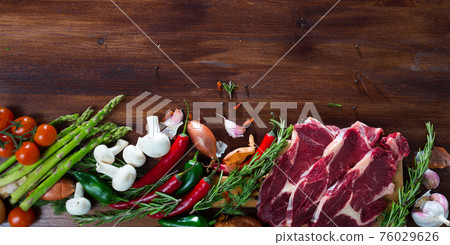 Raw beef and vegetables assortment on wooden desk, cooking ingredients Raw beef and vegetables assortment on wooden desk, cooking ingredients 76029626