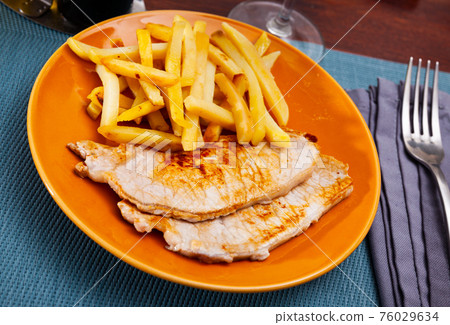 Baked pork meat with garnish of fried potato 76029634