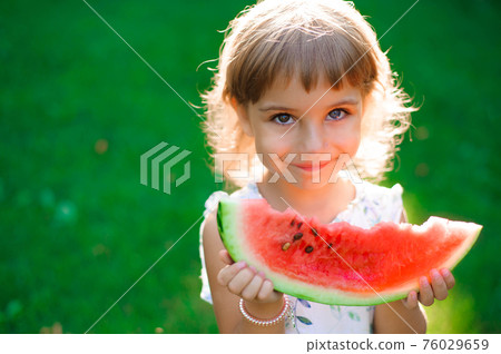 Cute little girl eating watermelon and enjoying picnic 76029659