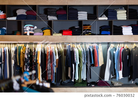 Interior of male clothing store with clothes on hangers and shelves Interior of male clothing store with clothes on hangers and shelves 76030032