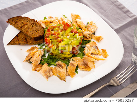 Grilled trout fillet served with salad guacamole with fresh tomatoes Grilled trout fillet served with salad guacamole with fresh tomatoes 76030287