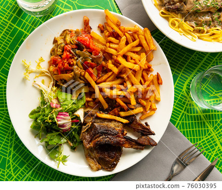 Portion of barbecued lamb ribs with french fries and vegetable garnish 76030395