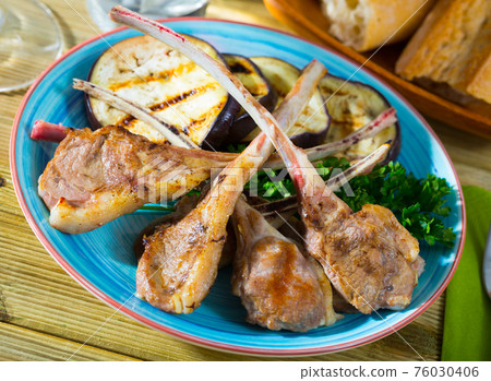 Tasty lamb ribs grilled with eggplants at plate with greens Tasty lamb ribs grilled with eggplants at plate with greens 76030406